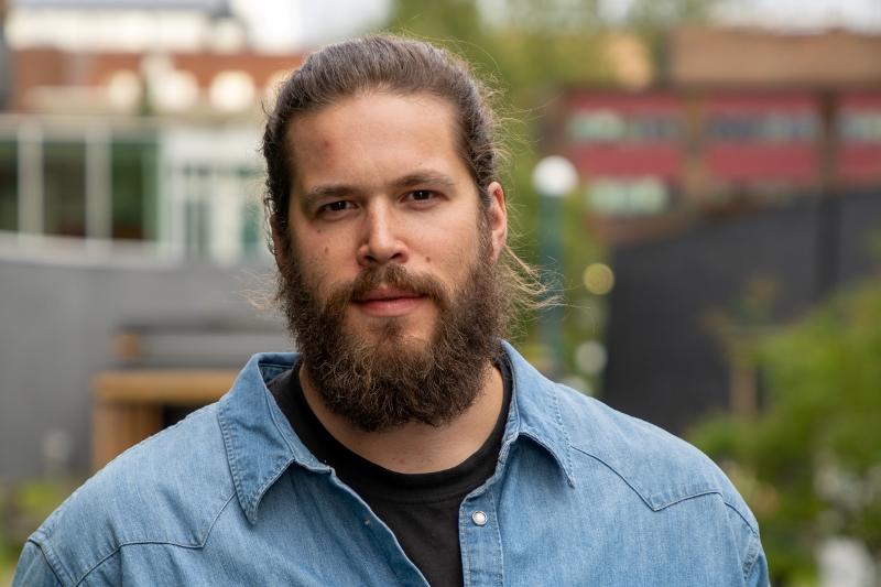 Portrett av ein mann, utandørs. Han har langt hår i hestehale og eit stort skjegg.